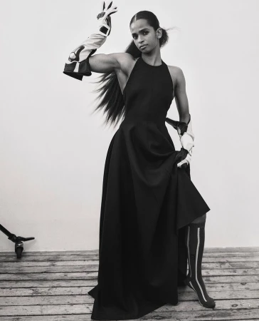 Model in long black dress wearing patterned arm guards and striped socks by Xavier Scott Marshall