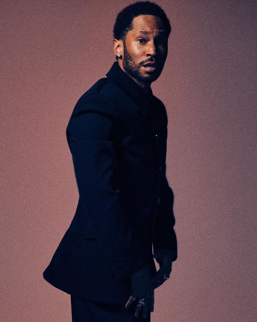 Black man in dark blazer standing against a neutral background by Xavier Scott Marshall
