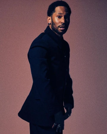 Black man in dark blazer standing against a neutral background by Xavier Scott Marshall
