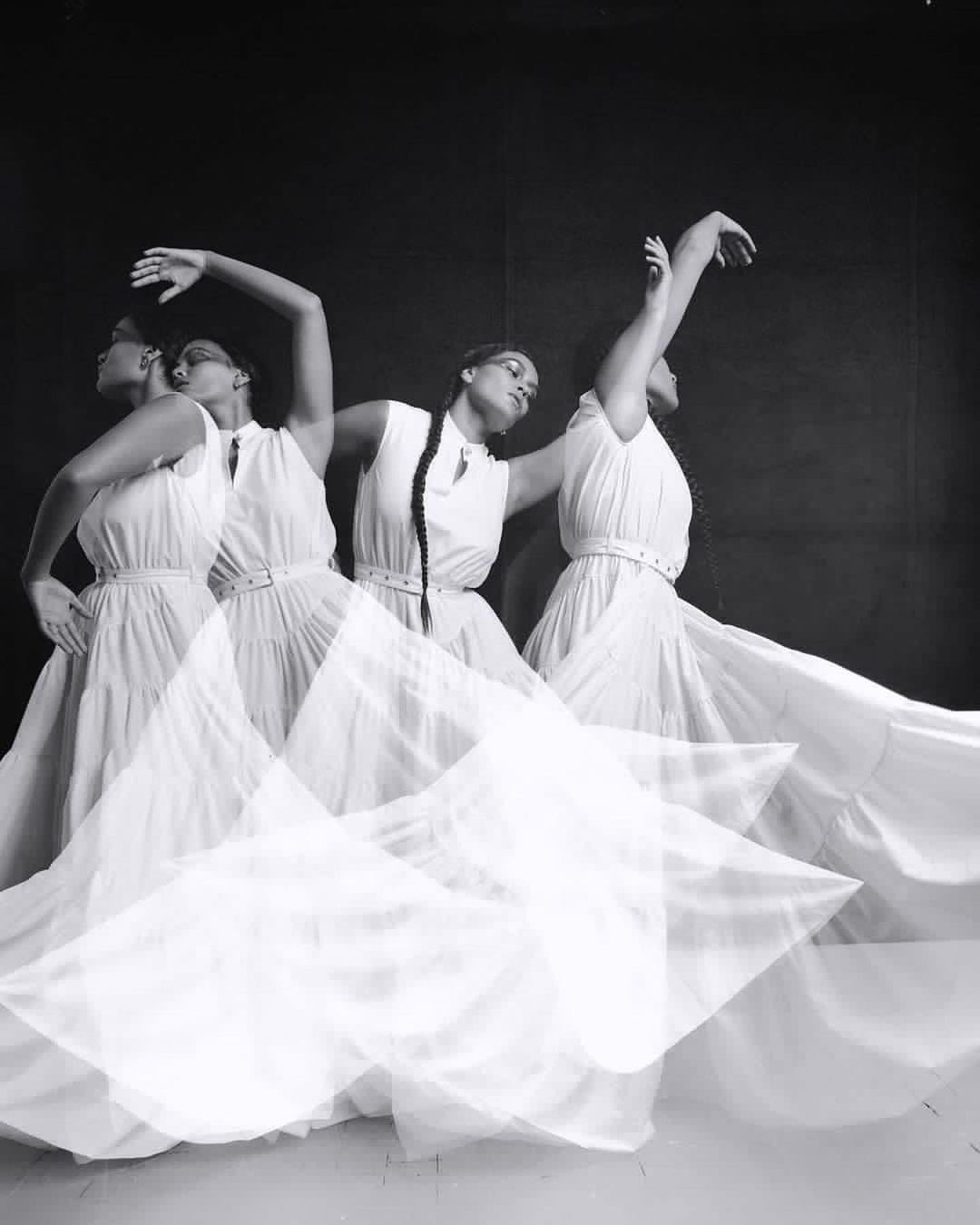 Multiple exposures of a woman in a flowing white dress, captured in a black and white image showcasing fluid motion and elegant dance poses.