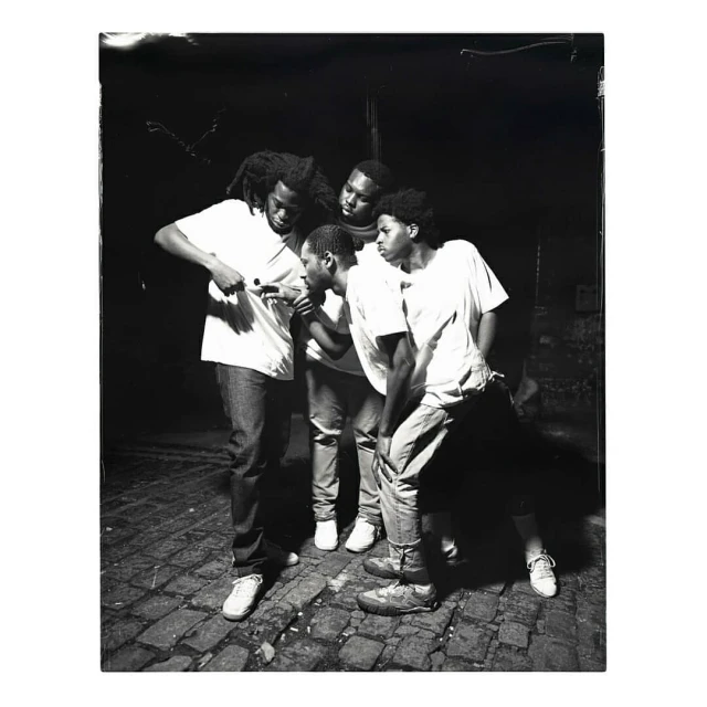 Monochrome portrait of five young adults outdoors, all looking in the same direction while standing on a brick-paved surface.