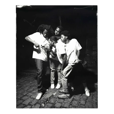 Monochrome portrait of five young adults outdoors, all looking in the same direction while standing on a brick-paved surface.