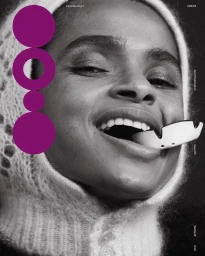 Close-up black and white portrait of a smiling woman wearing a knitted hood and holding a mouthguard in her mouth.