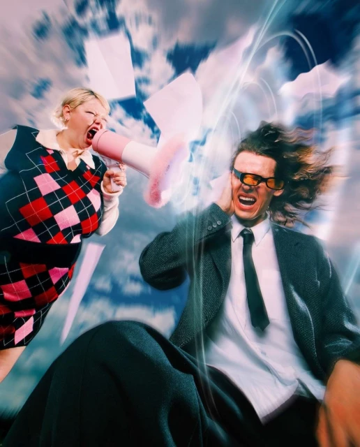 Woman yelling into a megaphone at a man covering his ears, with scattered papers and a sky background. Stress and communication issues.