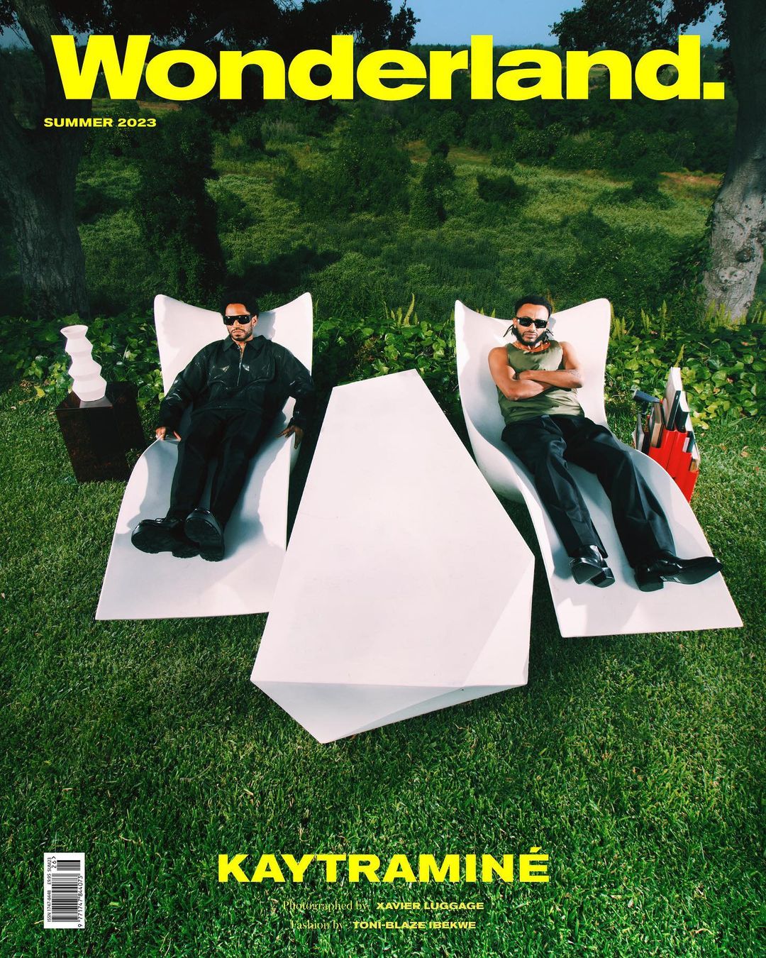 Magazine cover featuring Kaytranime reclining on white lounge chairs on green grass. Wonderland Summer 2023 issue. Fashion editorial.