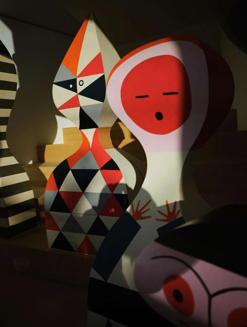 Geometric art installation with stylized figures and bold colors, showcasing graphic design and modern artistic expression in indoor setting.