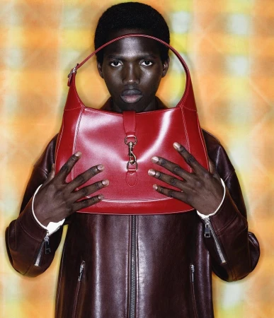 Man holding a glossy red leather shoulder bag in front of his face by photographer Yago Castromil