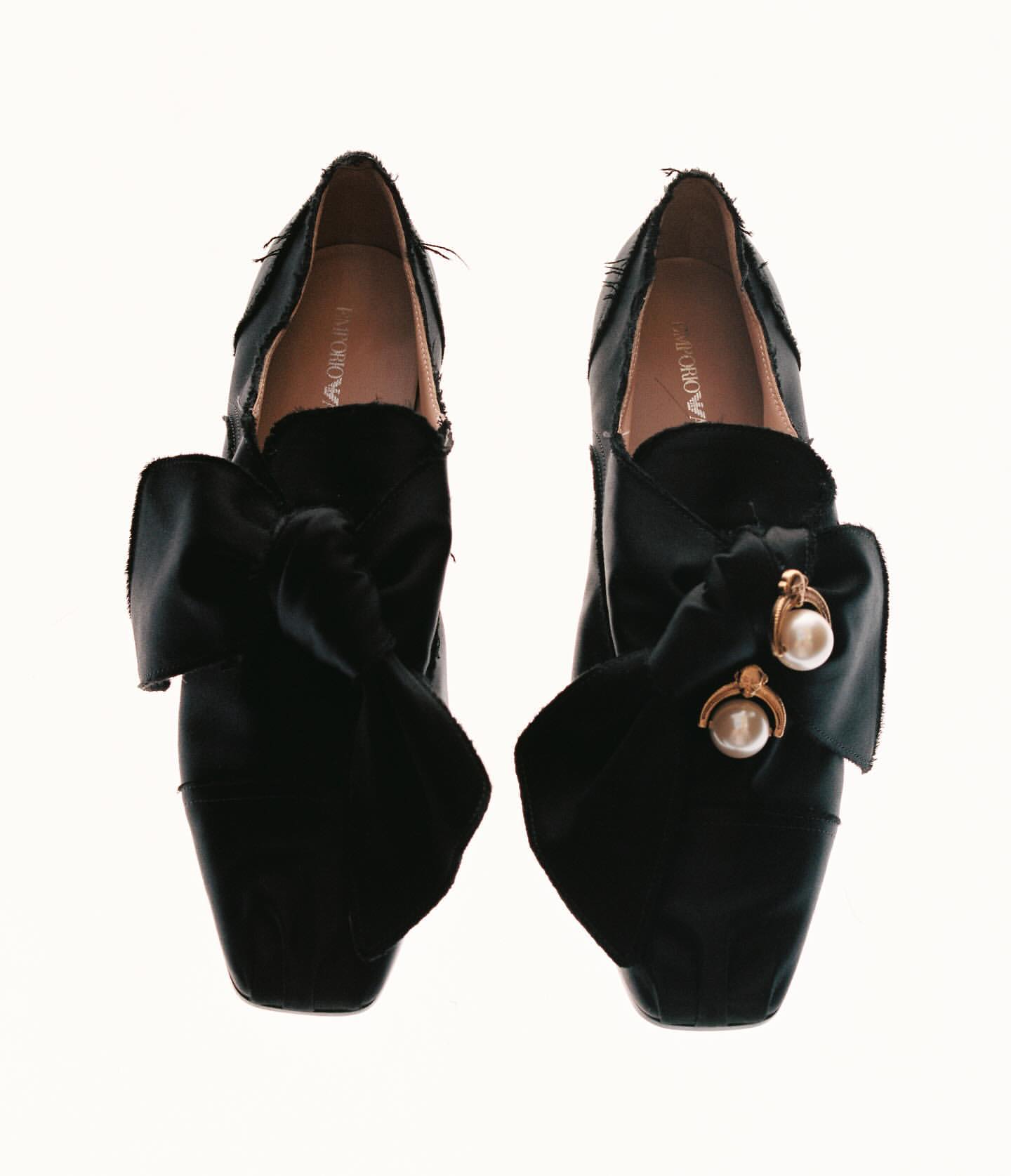 Elegant black Emporio Armani shoes featuring large satin bows with pearl and gold-tone accents, photographed on a clean white background.