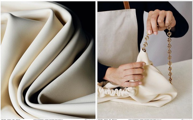 Close-up of cream-colored folded fabric alongside a person holding a cream-colored leather bag with a gold chain strap indoors.