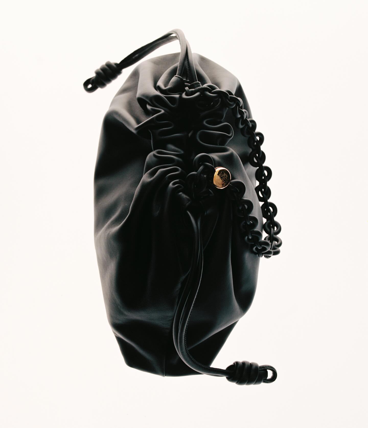 Elegant black satin drawstring pouch or handbag with a decorative gold accent and a black beaded strap against a white background.