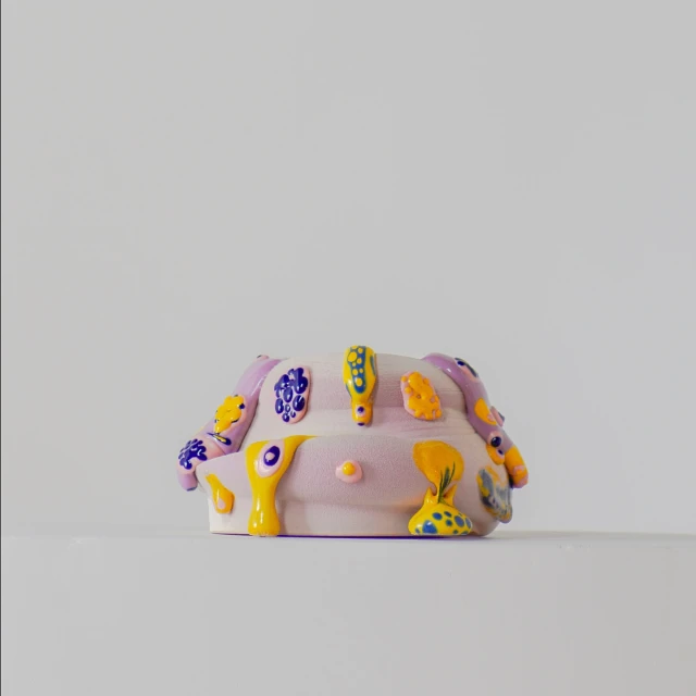 Unique handmade ceramic sculpture with colorful abstract decorations, set against a neutral background, creating a contemporary art piece.