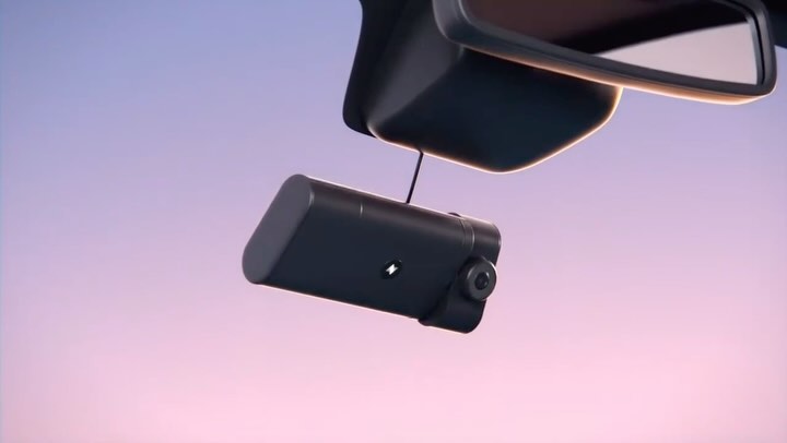 Dashboard camera mounted below a rearview mirror, with a lavender sky in the background, providing a clear view for safety.