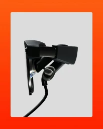 CGI rendering of black virtual reality headset with attached cable against a light grey background and bright orange border.