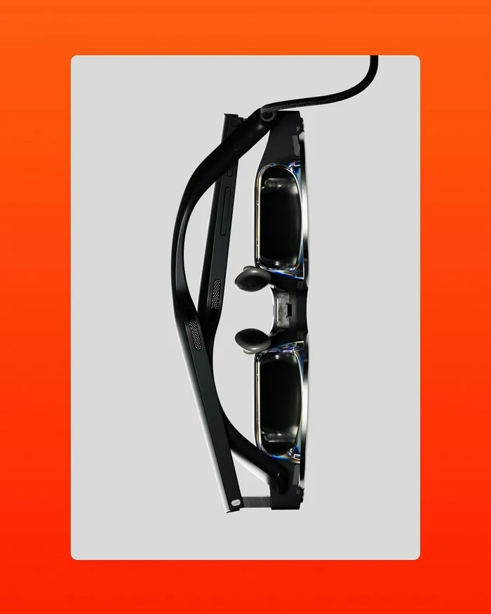 Close-up profile view of sleek black smart glasses set against a white backdrop framed in vibrant orange.