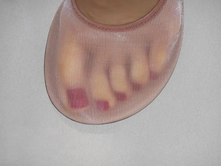 Close-up of a foot wearing a sheer, nude-colored sock, showing painted toenails and the sock's textured fabric against a neutral background.