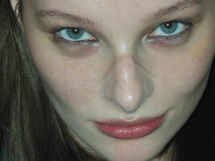 Close-up portrait of a woman with bright blue eyes, dark hair, and subtle makeup, shot from a high angle by Yana Van Nuffel.