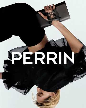 Model in a black sheer ruffled top holding a dark leather clutch against a plain white background