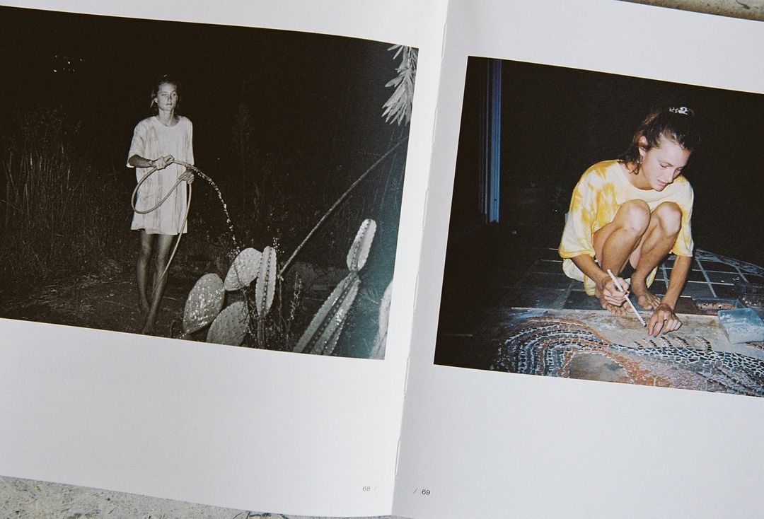 Book spread with an adult female watering plants in a dark garden, and another female working on art in an indoor, low-light setting.