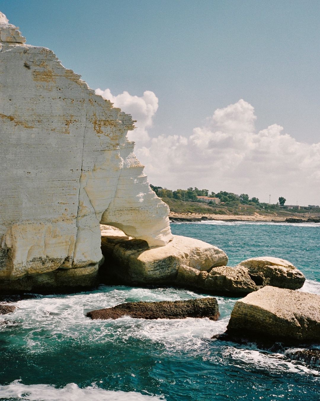 Coastal landscape with a large chalk cliff formation, blue sea, and clear sky, showcasing natural beauty and serene atmosphere.