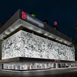 Exterior view of a large retail building at night featuring an illustrative monochrome facade mural and illuminated signage.