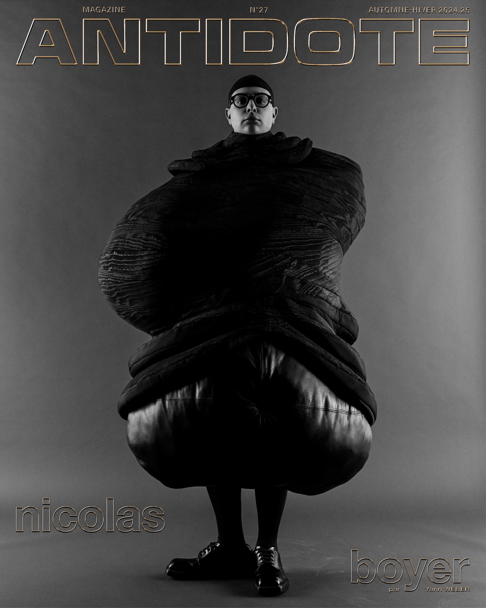 Magazine cover featuring a person wearing black clothing and round eyeglasses, with 'Antidote' magazine title above on a grey background.