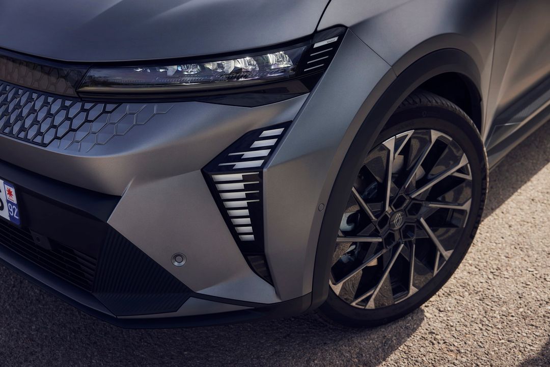Close-up of a grey car featuring a distinctive honeycomb grill, modern headlights, black multi-spoke wheels, and sleek aerodynamic design.