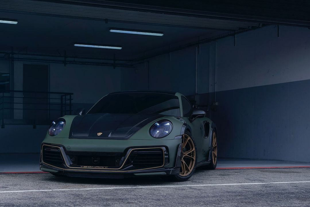 Olive green Porsche 911 Turbo with black hood parked indoors, featuring gold rims and trim; Techart logo visible on the front.