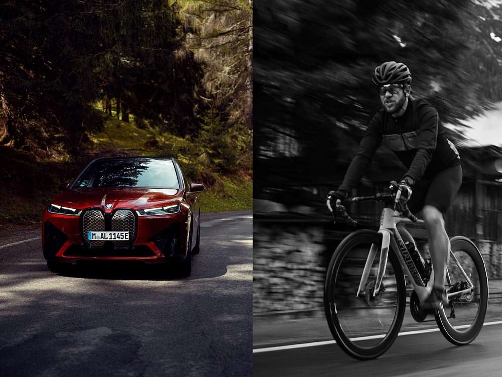 Split screen featuring a burgundy BMW on a winding road in a forest and a cyclist riding on a road in a black-and-white shot.