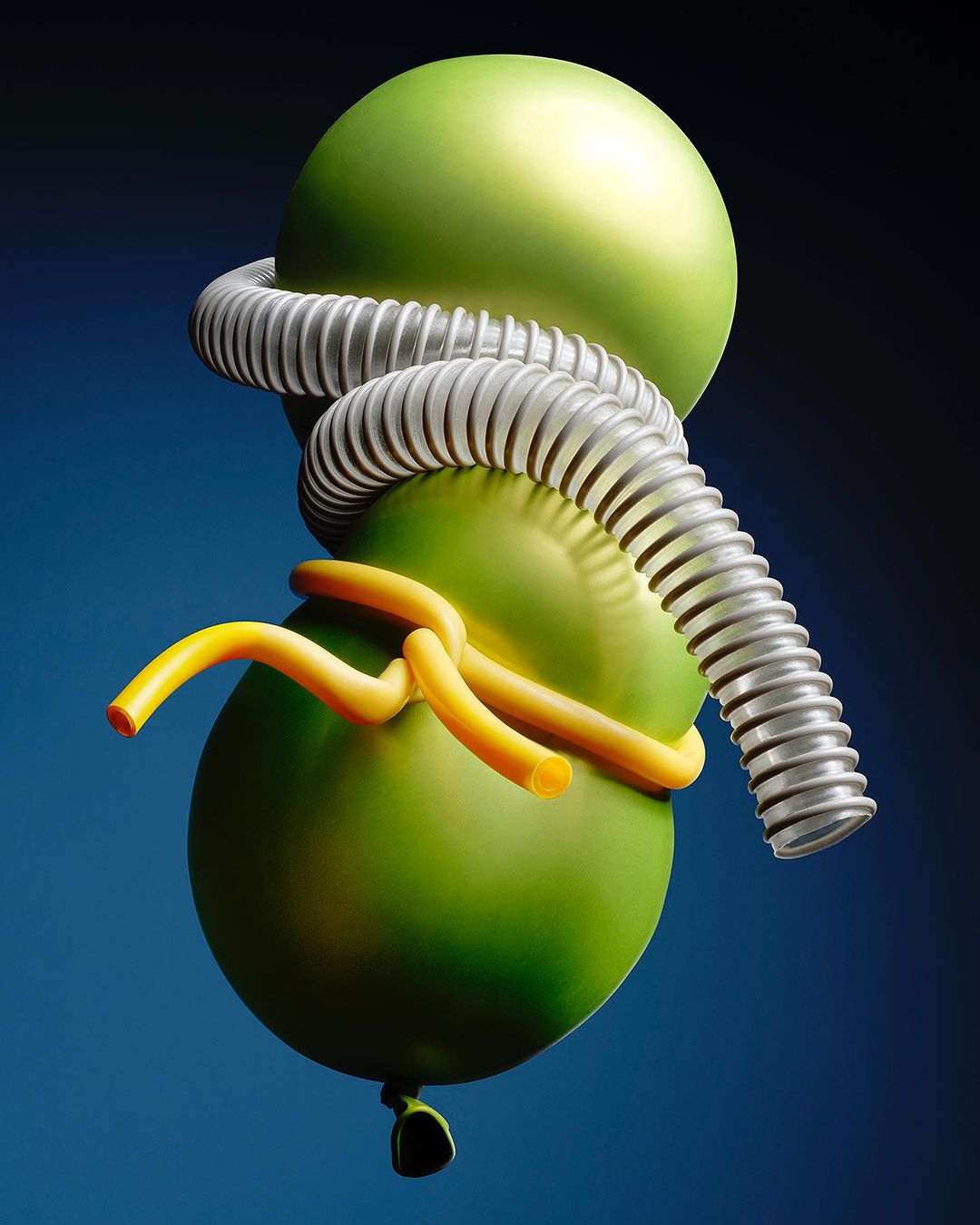 Abstract art featuring two green balloons joined by a silver corrugated tube and yellow cords against a gradient blue background.