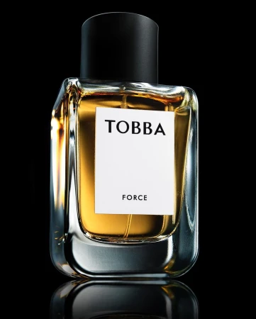 Close-up product shot of a Tobba Force perfume bottle with amber liquid against a dark black background
