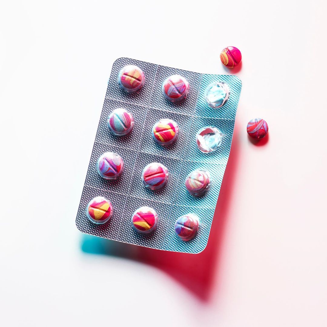 Close-up studio shot of blister pack with multi-colored pills on a white background, emphasizing pharmaceutical and healthcare context.