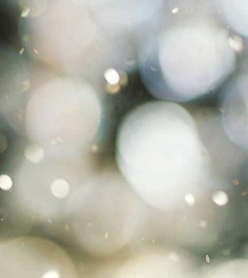 Abstract image with blurred light orbs in diffused white and grey tones, creating a bokeh effect ideal for backgrounds.