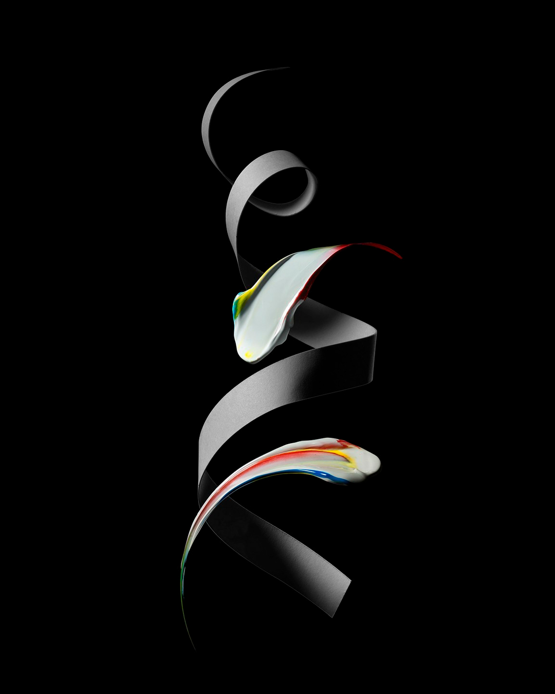Abstract still life featuring a swirl of glossy white paint with colorful accents, set against a stark black background for high contrast.