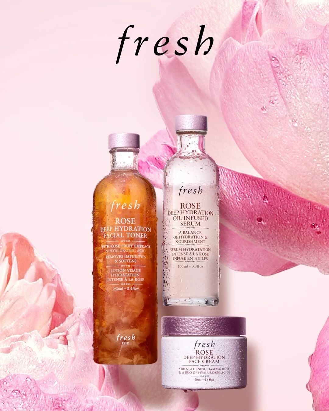 Three Fresh brand skincare bottles are displayed against a blurred pink rose background, featuring facial toner, oil-infused serum, and face cream.