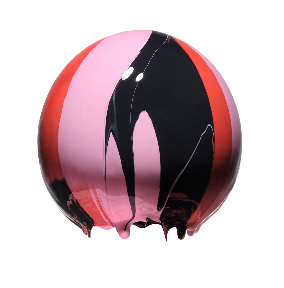Abstract sphere with drizzles of pink, coral, and black paint on a white background. The sphere's glossy surface reflects light.