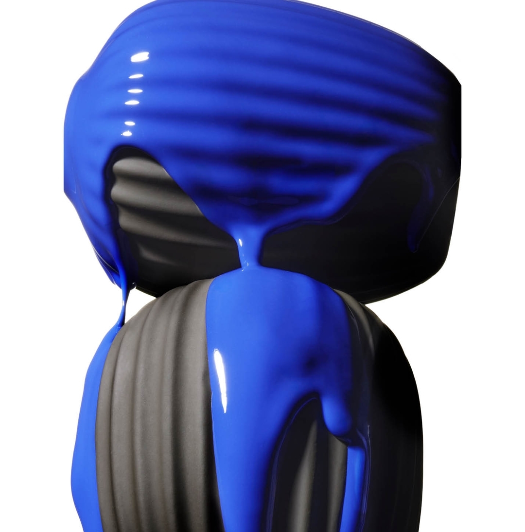 Sculpted forms are partially covered in vibrant blue liquid, creating a striking contrast of color and texture in a studio environment.