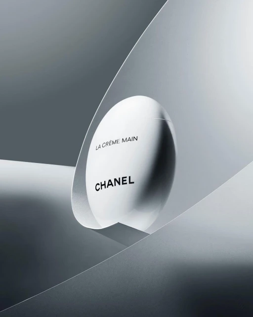 Chanel hand cream product shot. Minimalist composition featuring sleek packaging against a gradient gray backdrop. Beauty and luxury.
