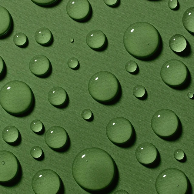 Macro photograph of water droplets of varying sizes scattered across a solid green surface with a soft, diffused light.