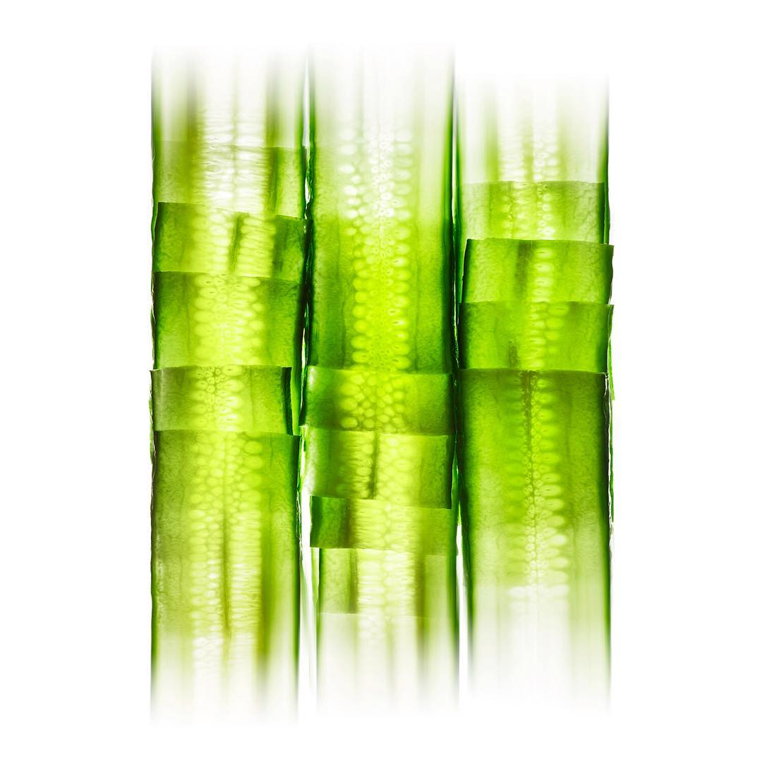 Close-up stack of green cucumber slices, illuminated with light shining through their translucent segments, creating a vibrant culinary image.