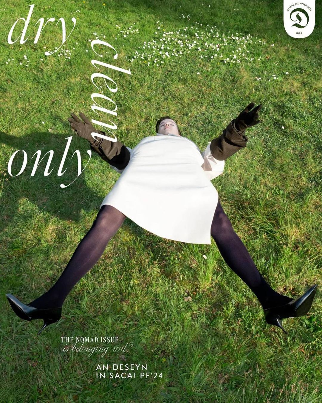 Fashion magazine cover shot: Model lies on green grass wearing a white dress, dark gloves, black tights and shoes; "Dry Clean Only" text.
