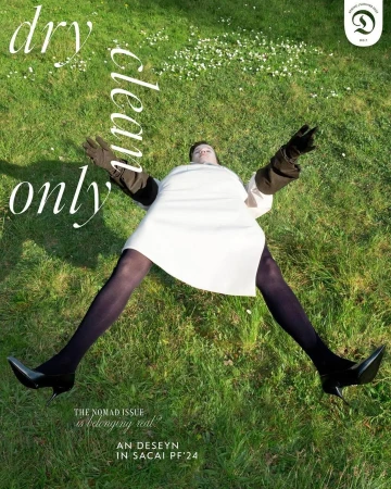 Fashion magazine cover shot: Model lies on green grass wearing a white dress, dark gloves, black tights and shoes; "Dry Clean Only" text.