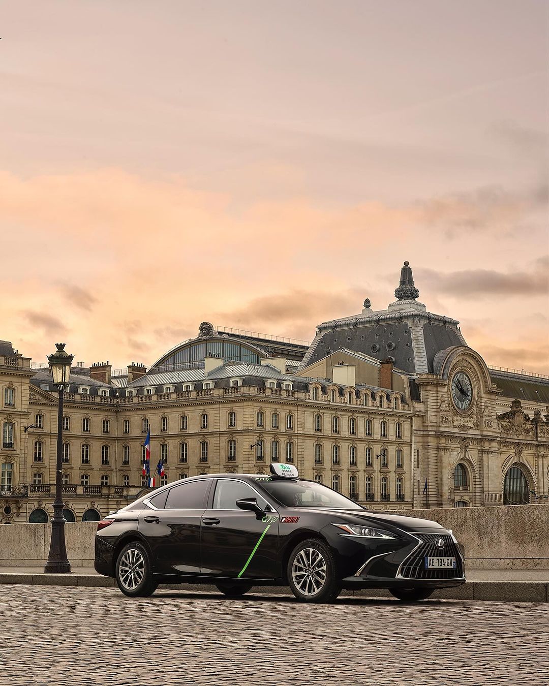 Black Lexus taxi parked in front of the Musée d'Orsay in Paris at sunset, highlighting automotive design and urban architecture.