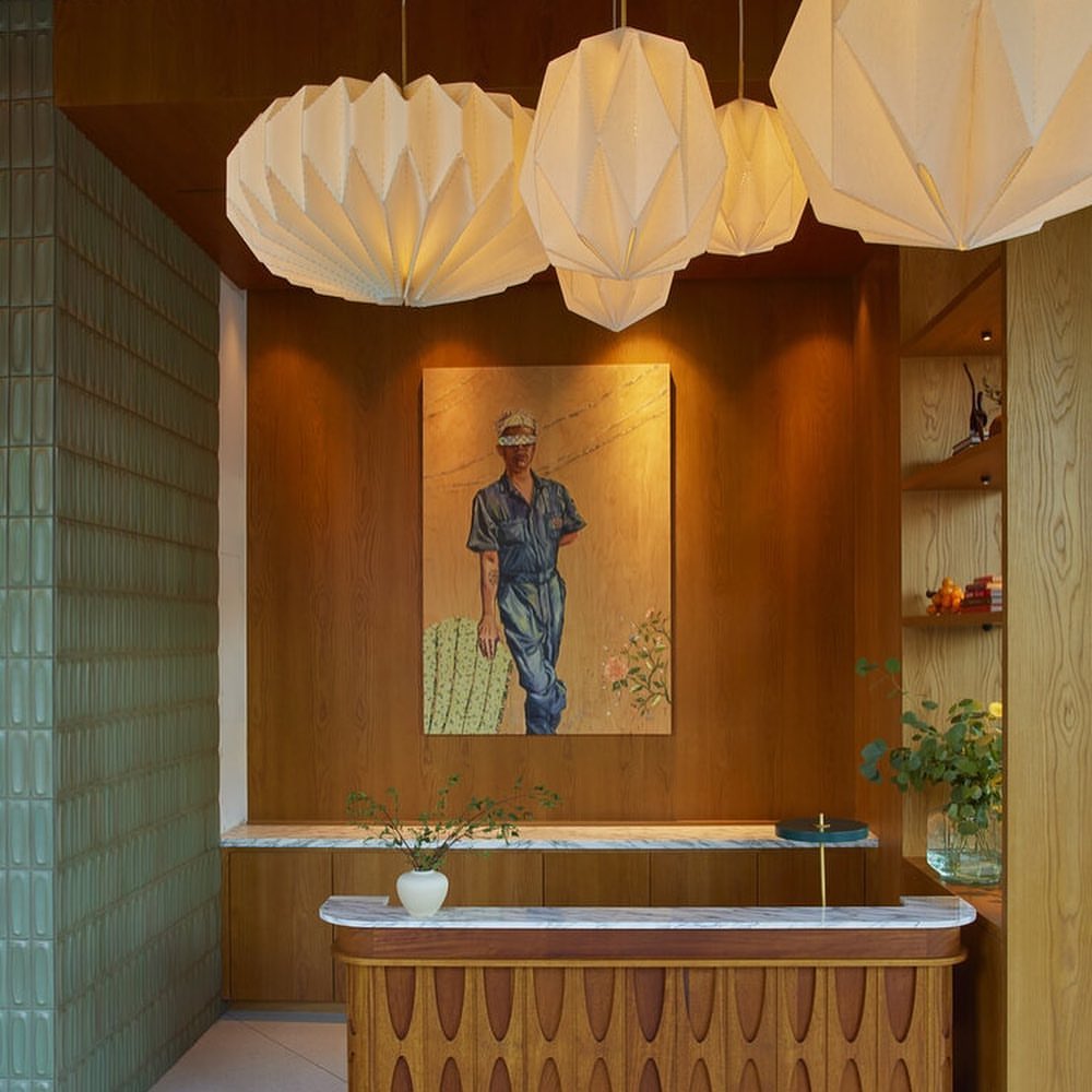 Stylish interior featuring a reception desk, modern lighting, and artwork, creating an inviting and contemporary atmosphere.