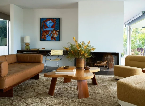 Living room interior with tan mid-century modern sofa, unique coffee table, and a vibrant art piece featuring a blue woman and tiger.
