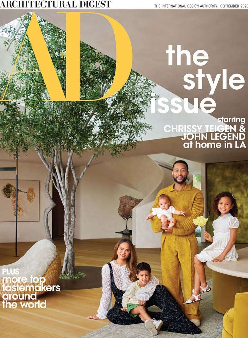 Architectural Digest cover with Chrissy Teigen, John Legend, and their children in a modern home interior, featuring a large tree.