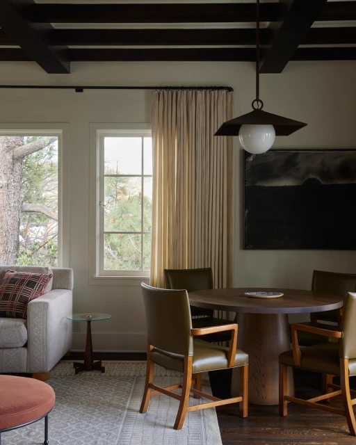 Interior view of a dining room with dark wood table and chairs, a modern light fixture, and a patterned area rug under furniture.