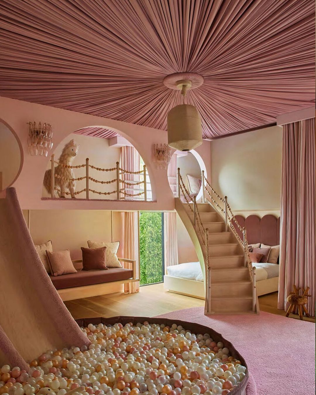 Whimsical child's bedroom interior with a ball pit, slide, stairs to a bed, and a rocking horse, all in soft pastel shades of pink.