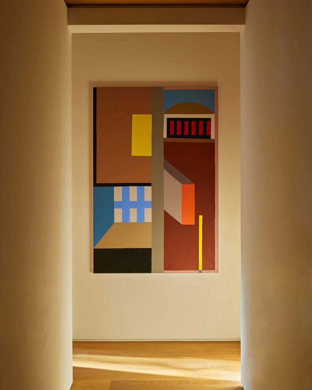 Geometric art piece in hallway with warm-toned walls and hardwood floor, creating a modern and inviting architectural space.