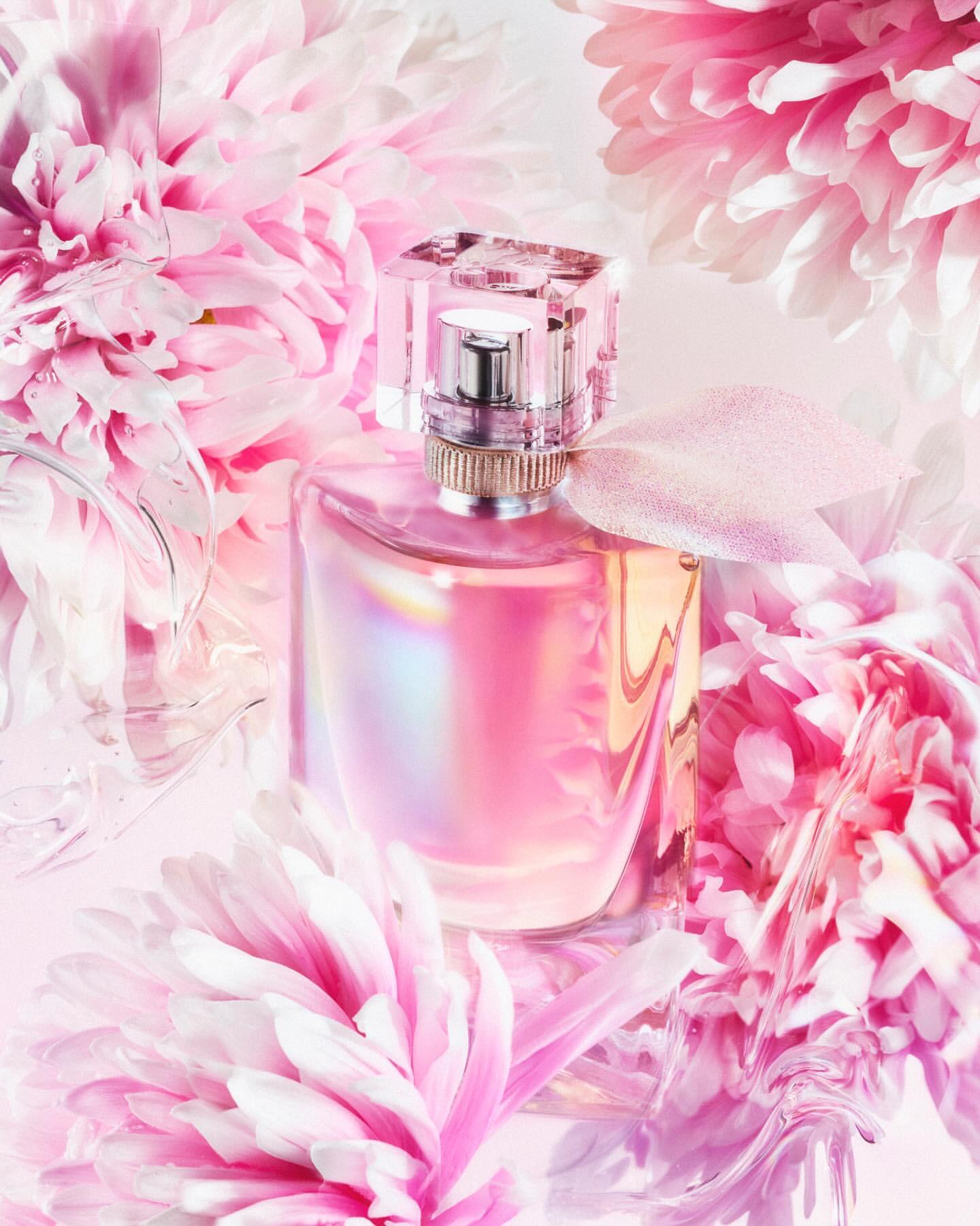 Pink perfume bottle with a clear cap surrounded by blooming pink flowers creates a soft, elegant, and floral-themed presentation.