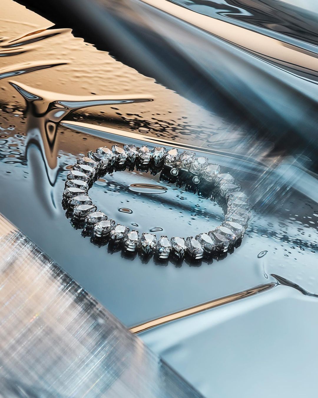 Close-up of a crystal bracelet on a wet metallic surface. Abstract composition featuring reflective surfaces and clear water droplets.